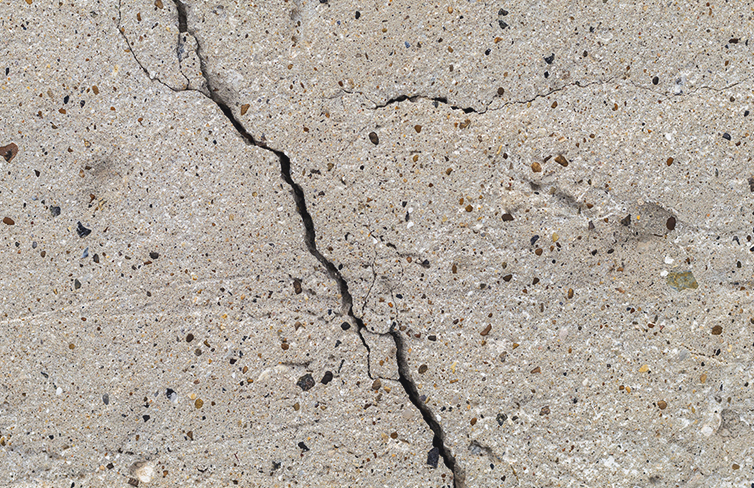 Rough textured surface of a cracked concrete foundation slab.